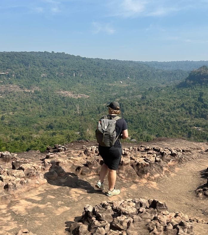 Solo traveler wearing backpack, overlooking a scenic mountain trail with lush greenery. Inspiring Solo Female Travel: Itineraries & Inspiration