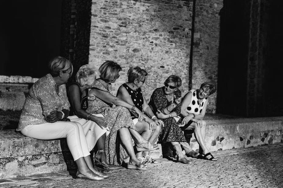 A group of women laughing and chatting on a stone bench, showing how easy it can be to meet people when solo travelling.